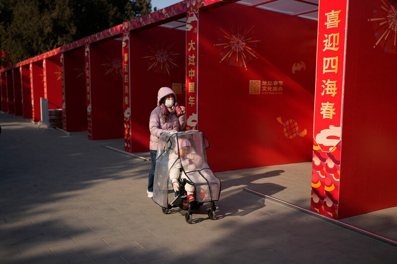 2025年1月22日,一名女子推着婴儿车,走过北京地坛公园准备迎接农历新年的空摊位。